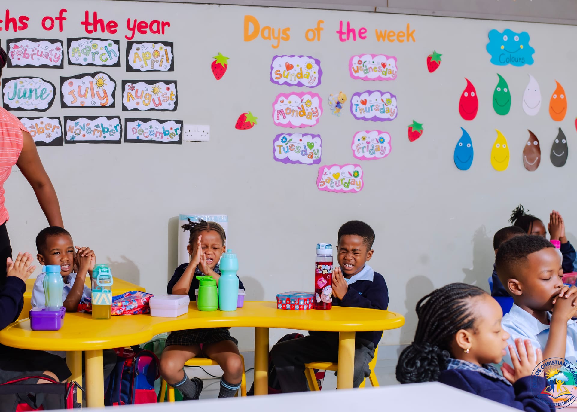 Children with hands together saying grace before their meal