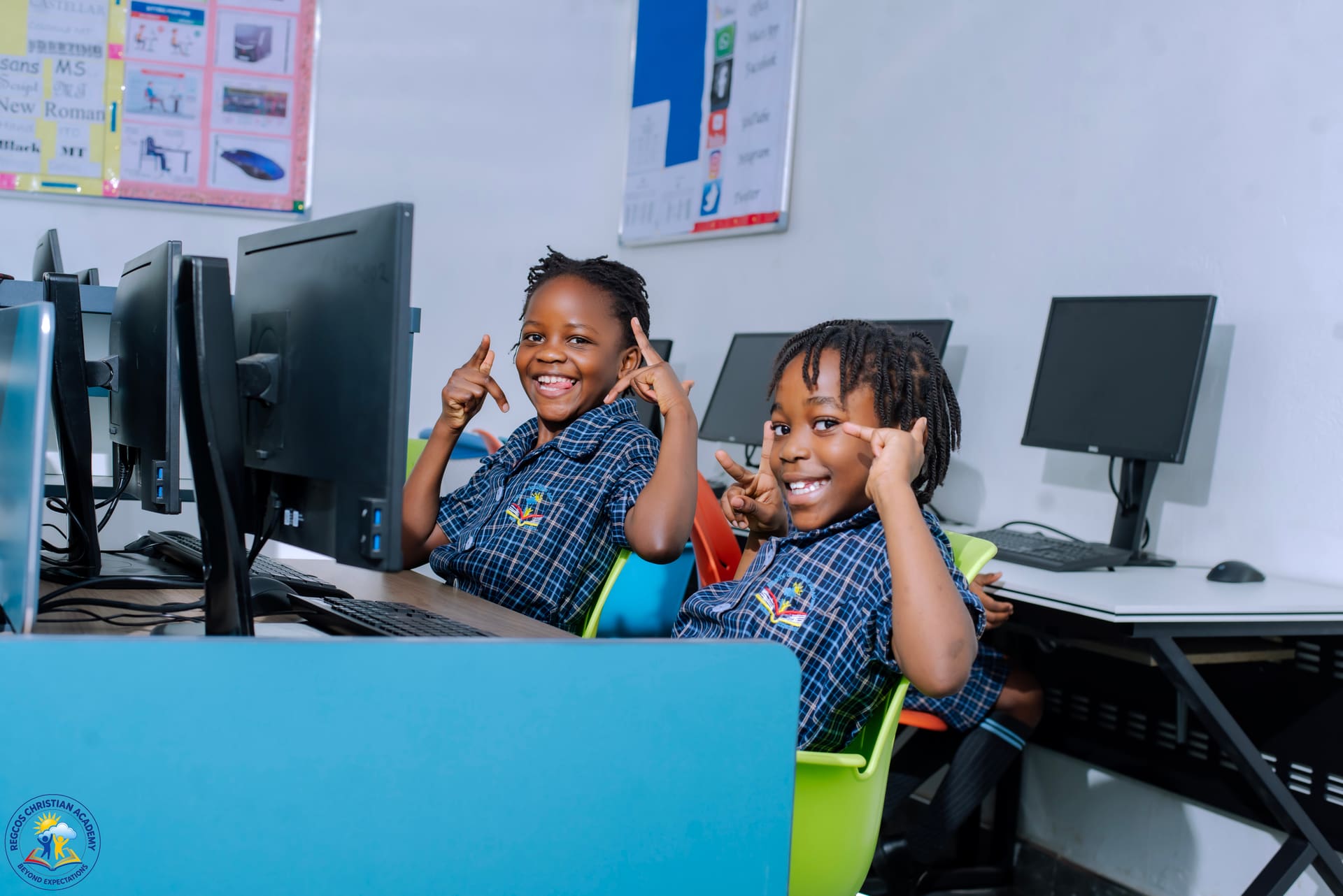 Two pupils smiling at their computers in the ICT lab
