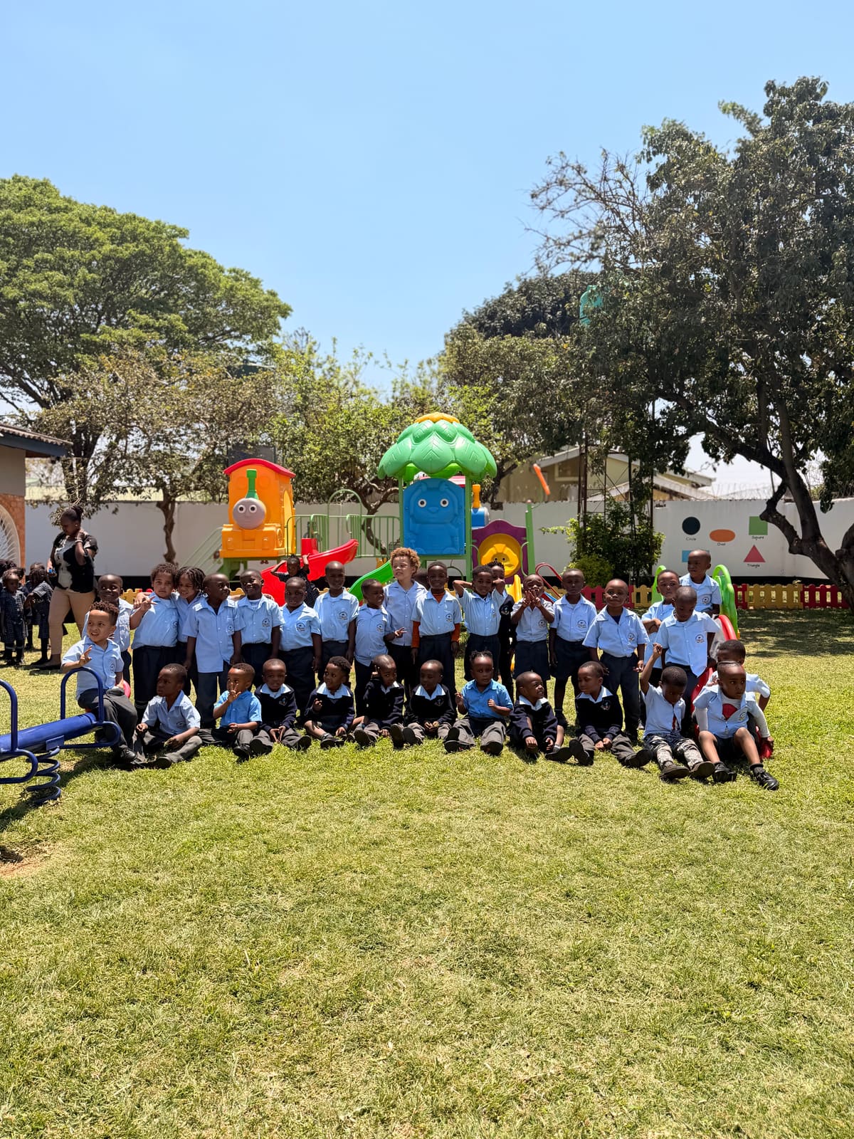 A large group of pupils on the lawn in front of the school playground