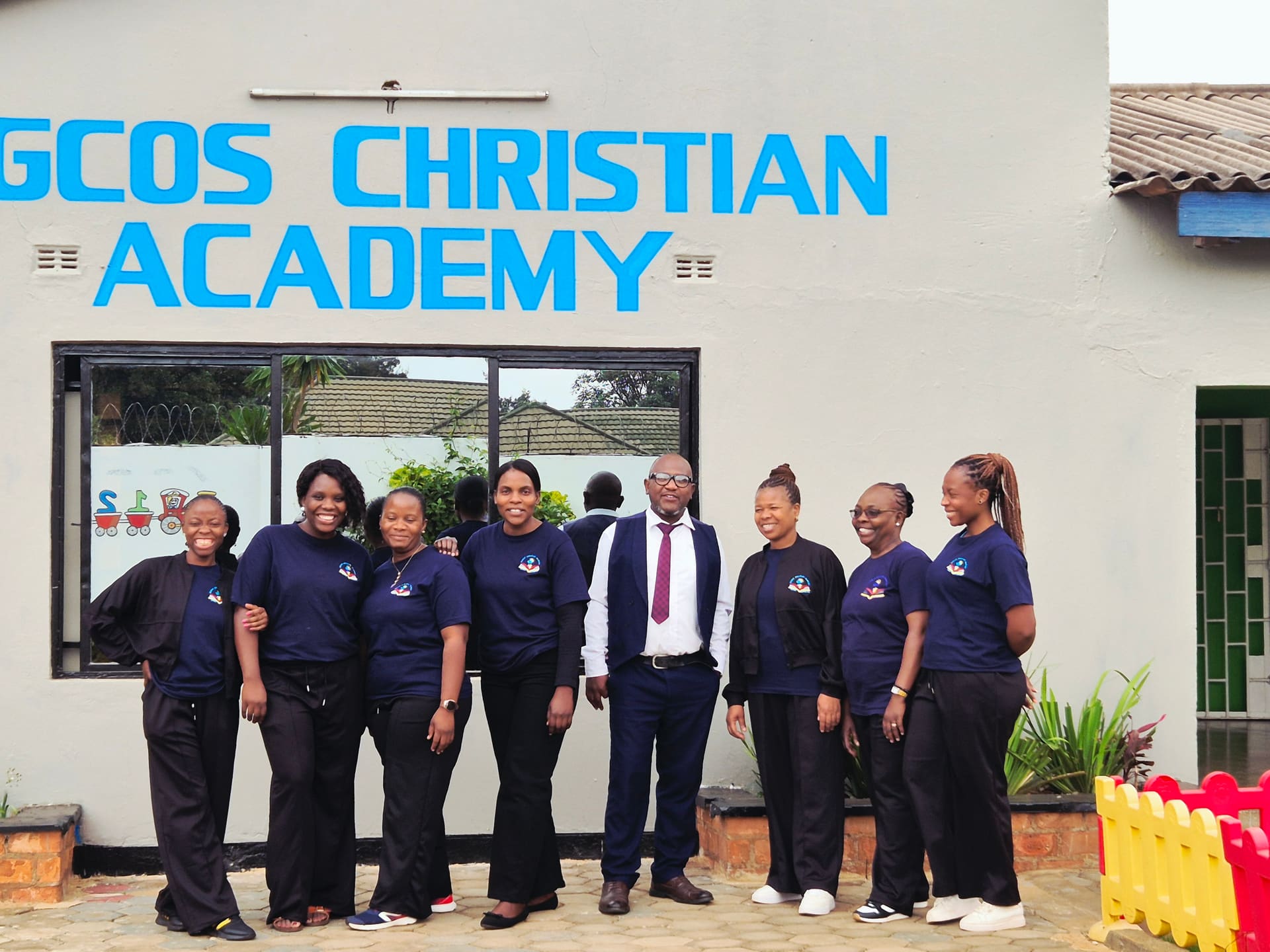 Regcos Christian Academy staff standing together outside the school entrance