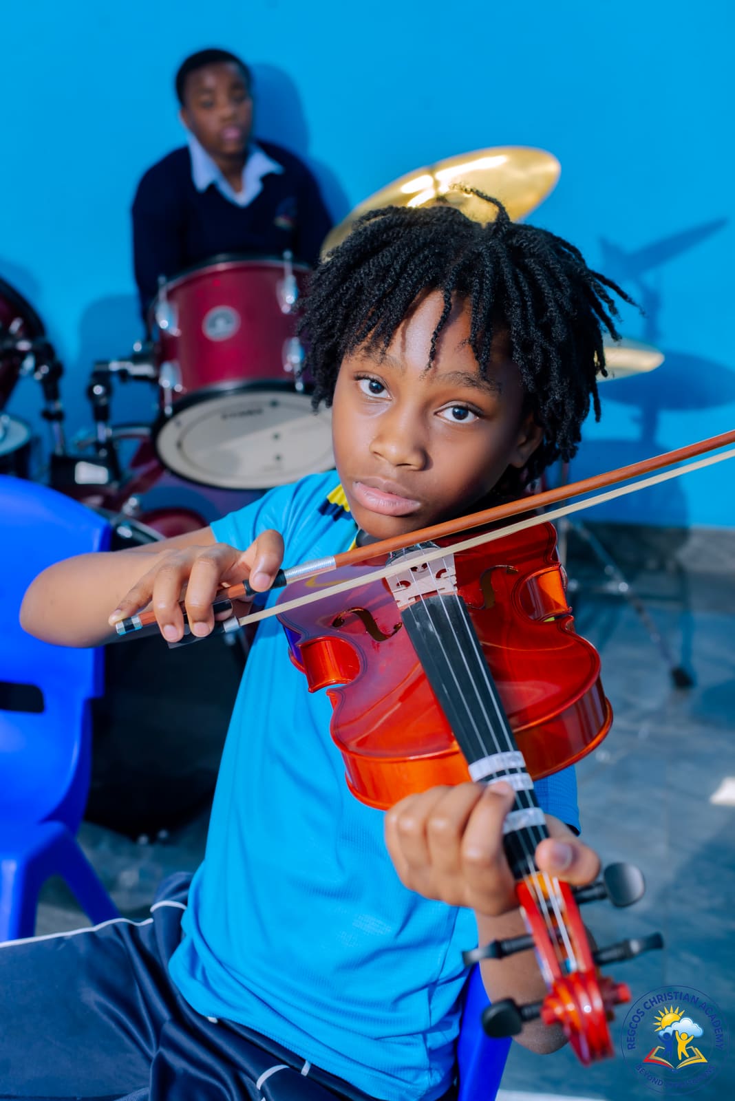 A pupil holding a violin and bow during music club